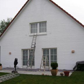 Fassadenanstrich in weiß mit weiß lackierten Fenstern an einem Einfamilienhaus.