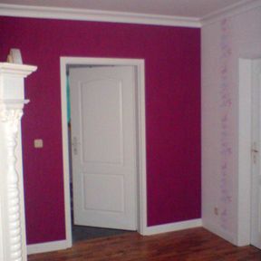 In Magenta gestrichene Wand. Oben und unten wurde ein schmaler Rand weiß gelassen, der zur weißen Tür passt.