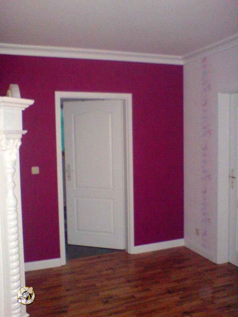In Magenta gestrichene Wand. Oben und unten wurde ein schmaler Rand weiß gelassen, der zur weißen Tür passt.