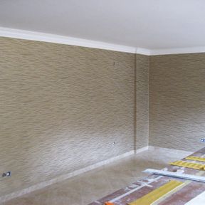 Wandgestaltung eines Innenraumes mit Tapete, die in beigefarben und Wellenmuster das flächig über die ganze Wand geht